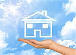 House icon on hand. Background of blue sky, clouds and sun