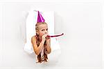 Little party girl with hat and whistle looking out on blast hole in paper - with copy space