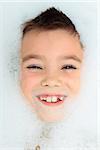 Seven years boy in a bubble bath filled with soap foam