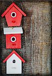 Three birdhouses painted with red and white colors on old wooden background