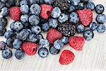 Fresh blueberry, blackberry and raspberry on wooden table