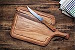 Cutting board and a kitchen knife on old wooden background. Top view