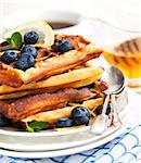Lemon blueberry waffles with honey, zest, fresh berries and cup of tea, soft focus