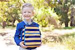 smiling little schoolboy holding lunchbag ready to go to school, back to school concept