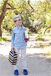 cute little schoolboy in glasses holding book and lunchbag ready to go to school, back to school concept