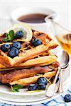 Lemon blueberry waffles with honey, zest, fresh berries and cup of tea