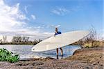 senior male paddler is launching his paddleboard on a lake, early spring in Colorado