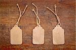 three blank paper price tags with a twine against a rustic wood