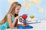 Little girl studies the solar system in geography class - looking at the scale model of planets