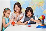 Kids making a scale model of the solar system in science class - helped by their teacher