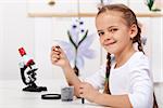 Young girl study plants in biology class - holding a seedling and test tube