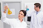 Scientists looking attentively at beakers in laboratory