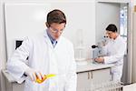 Scientists working attentively with test tube and microscope in laboratory