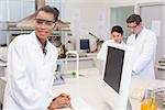 Happy scientist smiling at camera while colleagues working together in the laboratory