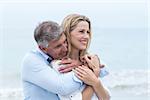 Happy couple hugging each other by the sea at the beach