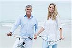 Happy couple cycling together at the beach