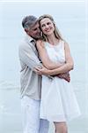 Happy couple standing by the sea and hugging each other at the beach