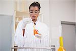 Concentrated scientist examining orange fluid in laboratory