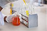 Scientist pouring orange fluid in test tube in laboratory