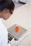 Scientist weighing beaker with orange fluid inside in laboratory