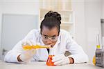 Concentrated scientist pouring orange fluid in laboratory