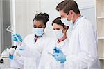 Scientists looking at beaker and taking notes in laboratory