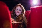 Smiling young woman watching a film at the cinema