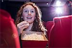 Smiling young woman watching a film at the cinema