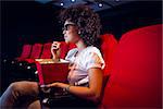 Young woman watching a 3d film and eating pop corn at the cinema