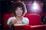 Smiling young woman watching a film at the cinema