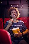 Smiling young man watching a film at the cinema
