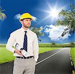 Young architect posing with hard hat and plan against road leading out to the horizon