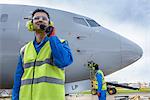 Airside engineer talking on radio near aircraft on runway