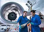 Engineers inspecting jet engine turbine blade in aircraft maintenance factory