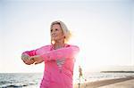 Senior woman stretching by beach