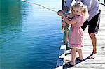 Mature man and daughter fishing from pier, New Zealand