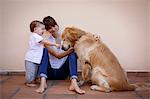 Mid adult woman with baby daughter petting dog in kitchen