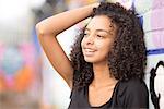 Teenager leaning against wall with graffiti