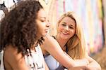 Teenagers relaxing against wall with graffiti