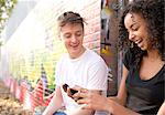 Teenage couple using smartphone against wall with graffiti