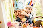 Portrait of girl with hands covering brothers eyes at kids birthday party