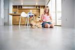 Girl playing with puppy on dining room floor