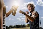 Male boxer training with personal trainer in park