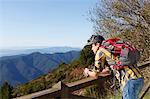 Hiker looking over valley against wooden handrail, Montseny, Barcelona, Catalonia, Spain