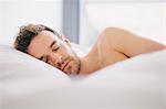 Young man lying on side asleep in bed