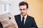 Young businessman reading morning newspaper at home