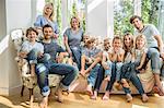 Group portrait of family and friends sitting on sofa in living room