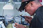 Jewellery craftsman using miniature blowtorch on platinum ring