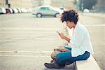 Young woman texting on smartphone in city parking lot