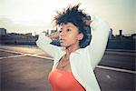 Young woman with hands in her hair on rooftop parking lot